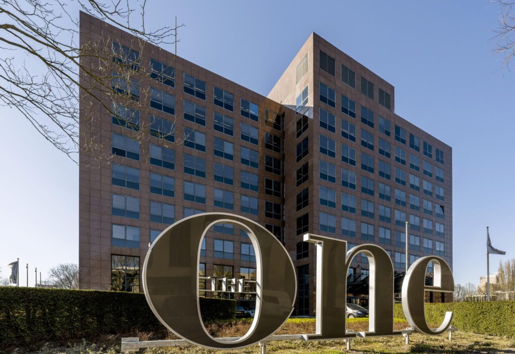 Modern kantoorgebouw aan de Prof. W.H. Keesomlaan met grote metalen letters "One" op de voorgrond.
